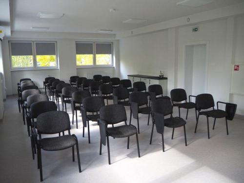 Przestronna sala szkoleniowa z rzędami krzeseł, przygotowana do organizacji konferencji, warsztatów i spotkań edukacyjnych. 